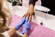 A professional manicure service in action with latex gloves and colorful nail polish.